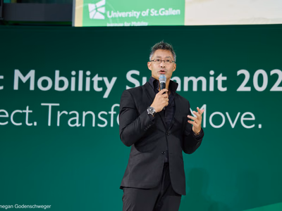 Dr. Philipp Rösler hält mit Mikrofon in der Hand die Laudatio vor der Kulisse des Smart Mobility Summit.