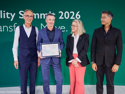 Claus Fleischer hält auf der Bühne seine Auszeichnung als Mobility Trailblazer 2026 in den Händen.